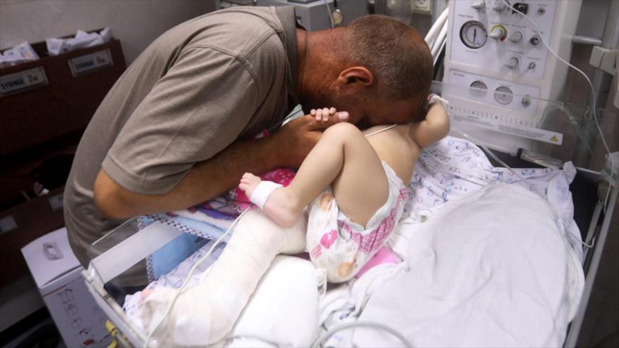 Un palestino sostiene a su bebé que fue sacado vivo de entre los escombros de un edificio, hospital Al-Shifa, Gaza, 15 de mayo de 2021. (Foto: APA)