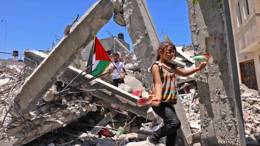 Niños palestinos entre los escombros de los edificios destruidos por agresiones israelíes en Jan Yunis, sur de Gaza, 19 de junio de 2021. (Foto: AFP)
