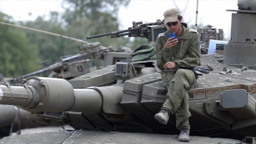 Un soldado israelí utiliza su móvil.