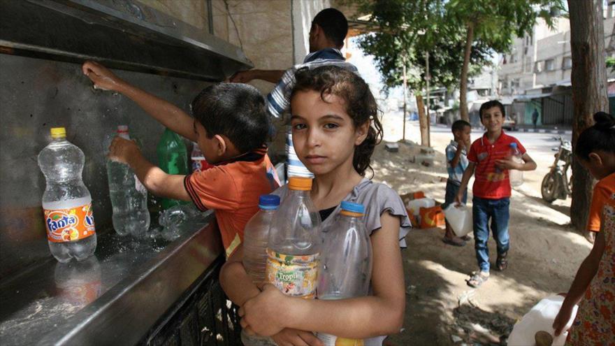 Niños palestinos llenan botellas con agua de un grifo público en Gaza, 1 de julio de 2014.