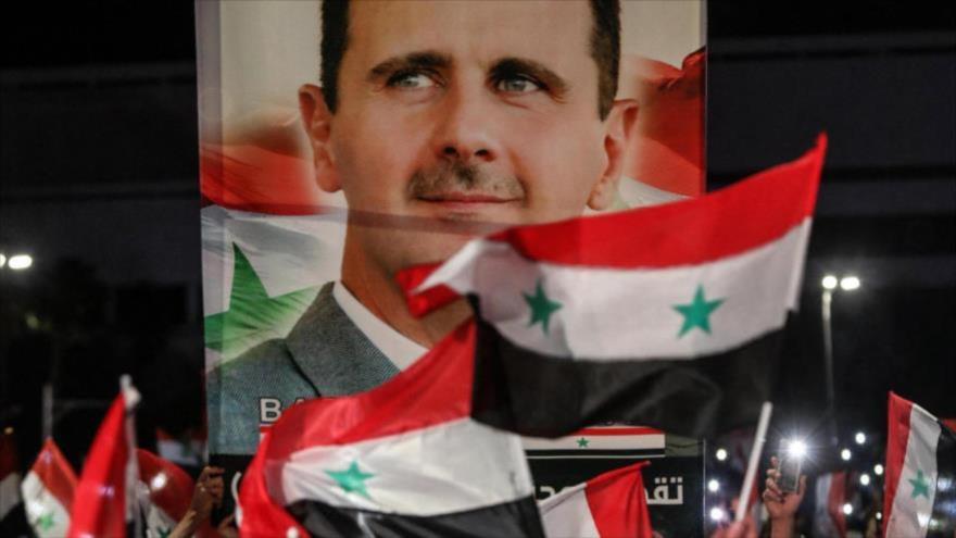 Los sirios ondean bandera y llevan una imagen del presidente Bashar al-Asad un día tras las presidenciales, 27 de mayo de 2021. (Foto: AFP)