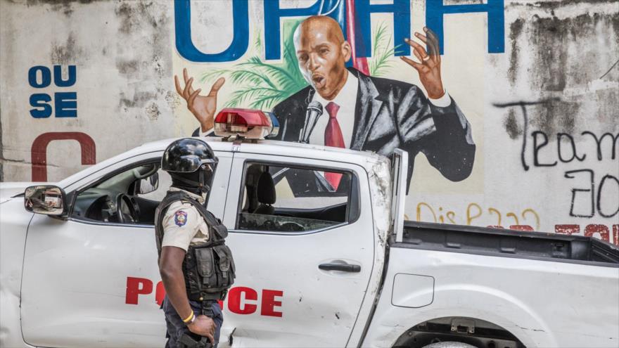 Un agente de la Policía mira a un mural del presidente fallecido de Haití, Jovenel Moise, 15 de julio de 2021. (Foto:AFP)
