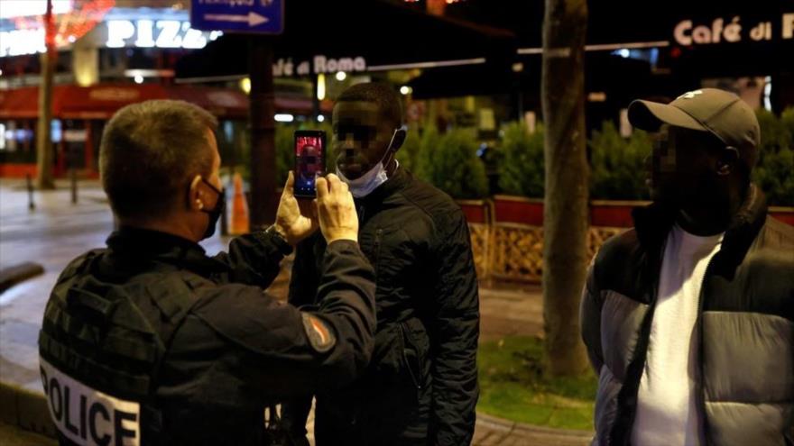 Un agente de policía gala escanea el rostro de un hombre negro en la avenida de los Campos Elíseos en París, la capital francesa. (Foto: AFP).