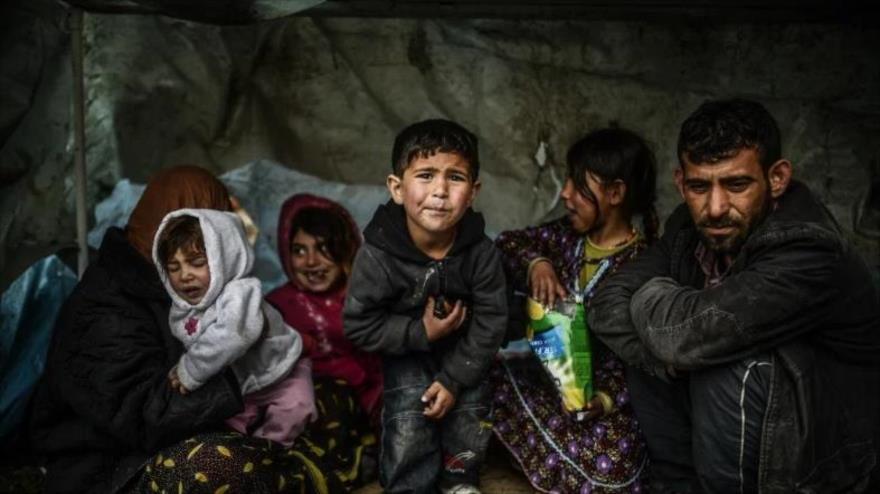 Una familia de refugiados sirios permanece bajo un refugio durante un día lluvioso en Uskudar, Estambul (Turquía), 8 de marzo de 2014. (Foto: AFP)
