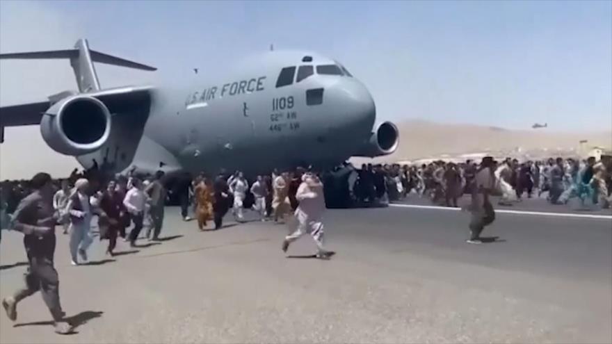 Afganos intentan subirse a un avión en el aeropuerto de Kabul para de huir del país tras la toma del poder por los talibanes, 16 de agosto de 2021.