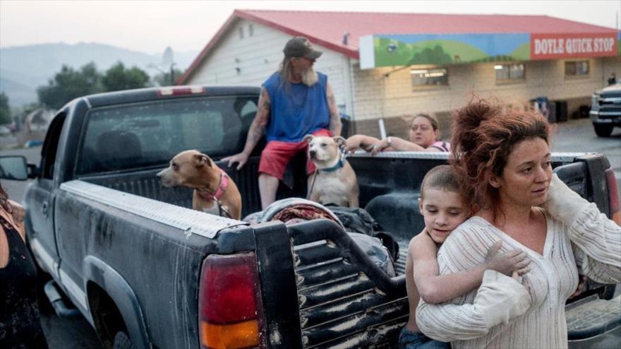 Una familia varada en una estación de servicio cerca del Dixie Fire, ubicado en el norte de California, está siendo evacuada. 17 de agosto de 2021 (Foto AP / Noah Berger)