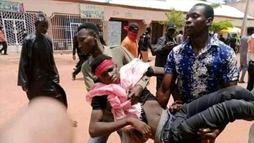 Hombres llevan el cuerpo de un doliente herido por la policia nigeriana en el Día de Ashura, Sokoto, Nigeria, 19 de agsto de 2021.