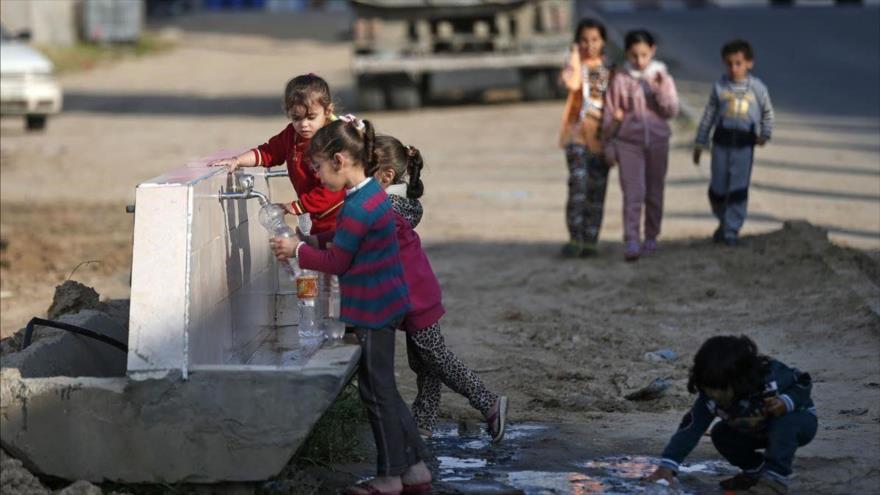 Niños palestinos llenan botellas de agua en un campo de refugiados en Jan Yunis, sur de la asediada Franja de Gaza. (Foto: AFP)