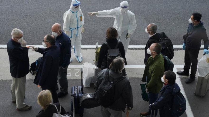 Un trabajador con cubiertas protectoras dirige a los miembros de la OMS tras su llegada al aeropuerto de Wuhan, China, 14 de enero de 2021. (Foto: AP)