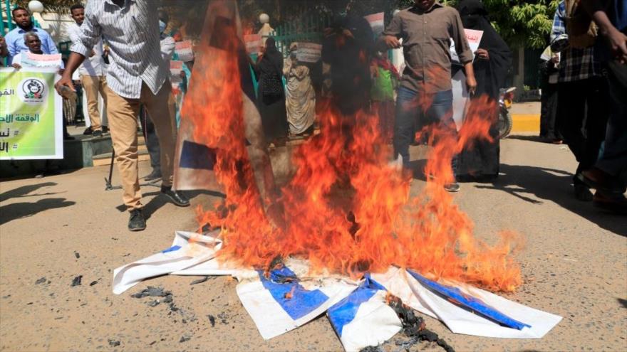 Manifestantes sudaneses queman bandera israelí en una protesta contra normalización con ese régimen, Jartum, 17 de enero de 2021. (Foto: AFP)