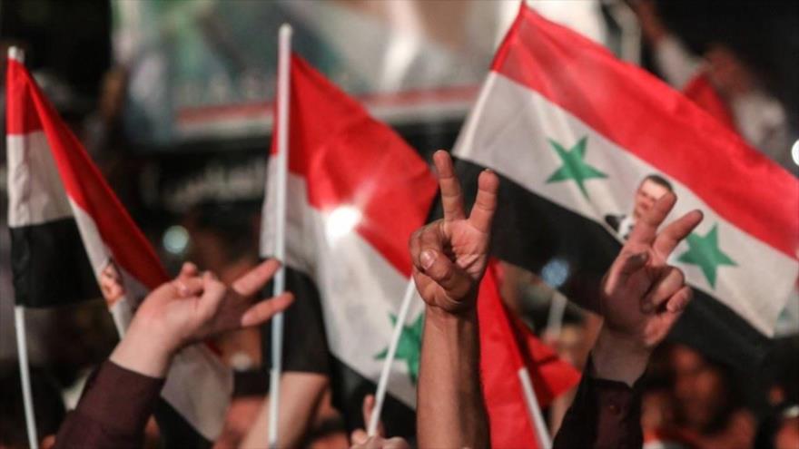 Sirios ondean banderas nacionales durante un mitin electoral en las calles de Damasco, 27 de mayo de 2021. (Foto: AFP)
