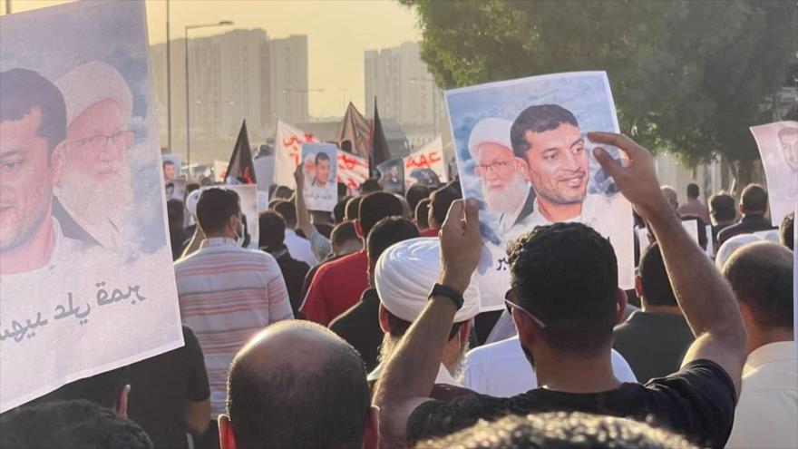 Manifestantes sostienen imágenes de Ali Qambar, preso bareiní que murió por negligencia médica durante su encarcelamiento, 25 de octubre de 2021.