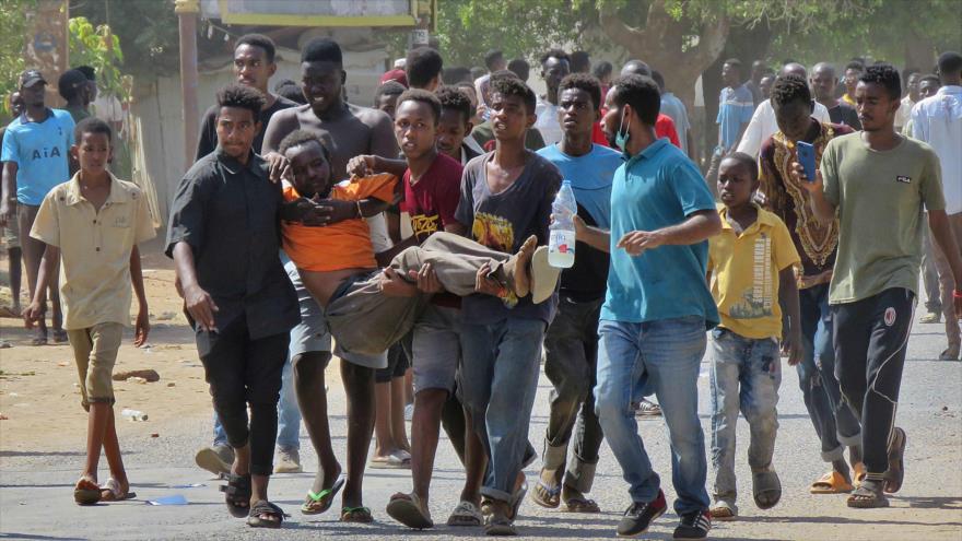 Los sudaneses llevan a un hombre herido durante un enfrentamiento con el grupo militar golpista, Jartum, Sudán, 25 de octubre de 2021. (Foto: AFP)