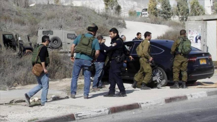 Soldados y policías de Israel inspeccionan el automóvil de un colono israelí que atropelló a una palestina en la ocupada Cisjordania.
