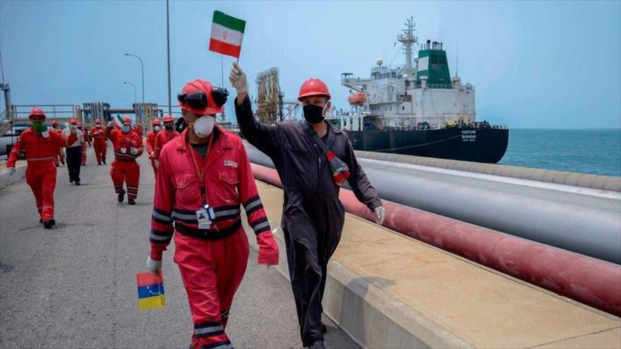 Trabajadores con banderas iraníes y venezolanas celebran la llegada del petrolero iraní “Fortune” a una refinería venezolana. (Foto: AFP)