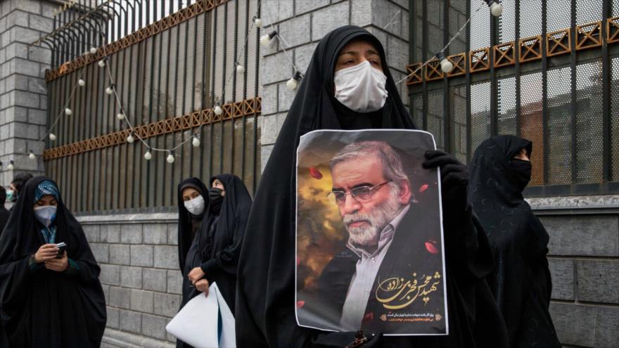 Una mujer iraní mantiene un cartel con la imagen del científico Mohsen Fajrizade tras su asesinato en un atentado terrorista.