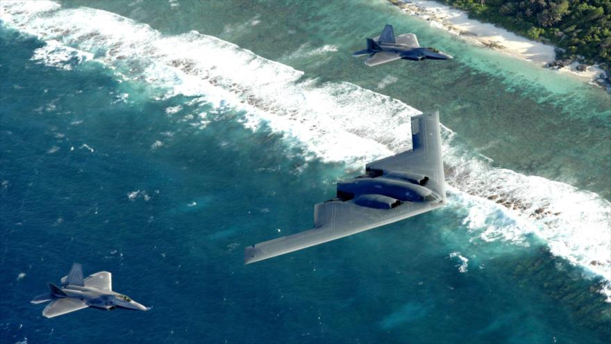Dos F-22 Raptors y un bombardero B-2 Spirit desplegados en la Base de la Fuerza Aérea Andersen, Guam, vuelan en formación sobre el océano Pacífico.