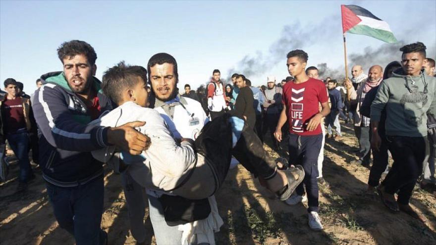 Manifestantes palestinos trasladan a un joven herido por disparos de las fuerzas israelíes a lo largo de Gaza, 14 de diciembre de 2018. (Foto: AFP)