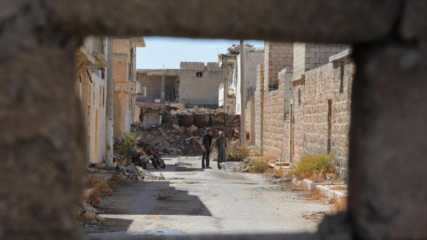 Sirios son fotografiados a través de un agujero en la ciudad norteña de Tadif, en Alepo, 7 de octubre de 2021. (Foto: AFP)