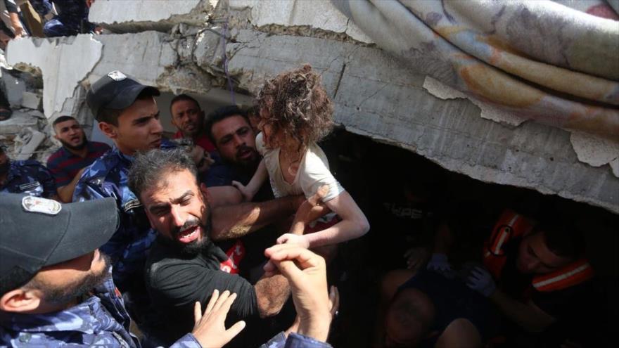 Palestinos recuperan a una niña de los escombros de un edificio destruido por un ataque israelí, Gaza, 16 de mayo de 2021.