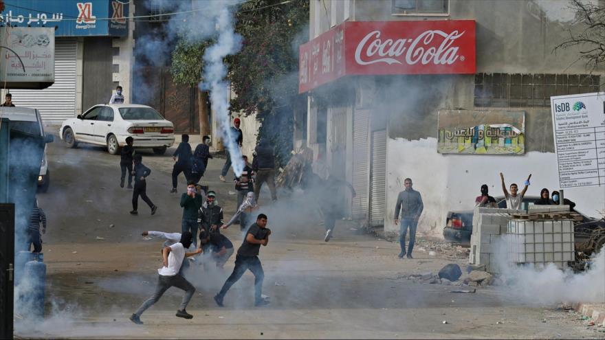 Jóvenes palestinos durante un enfrentamiento con los soldados israelíes en una aldea en la Cisjordania ocupada, 25 de noviembre de 2021. (Foto: AFP)