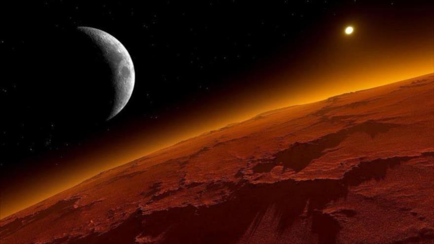 Se ve la luna desde la superficie de Marte, también conocido como el planeta rojo.
