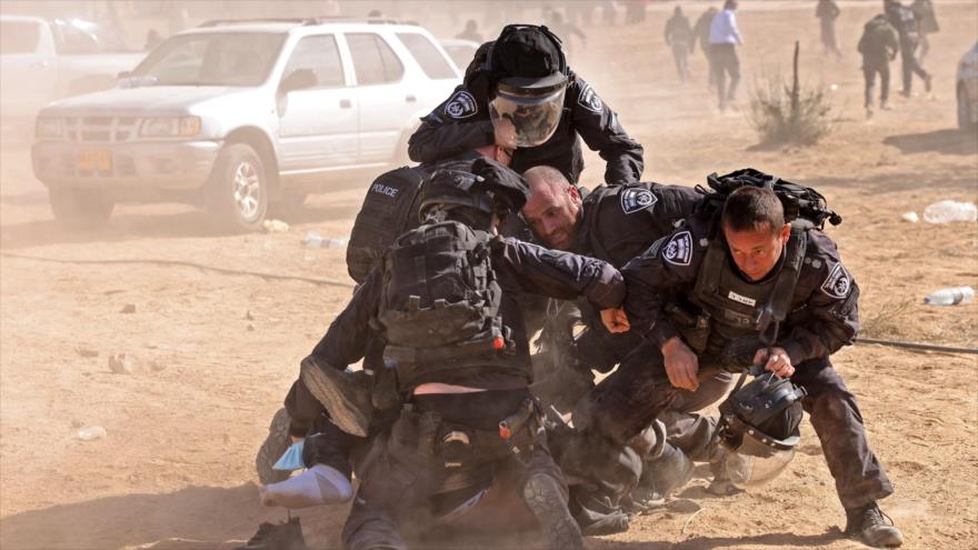Agentes de seguridad israelíes intentan detener a un hombre durante protesta de palestinos beduinos, desierto de Néguev, 12 de enero de 2022. (Foto: AFP)