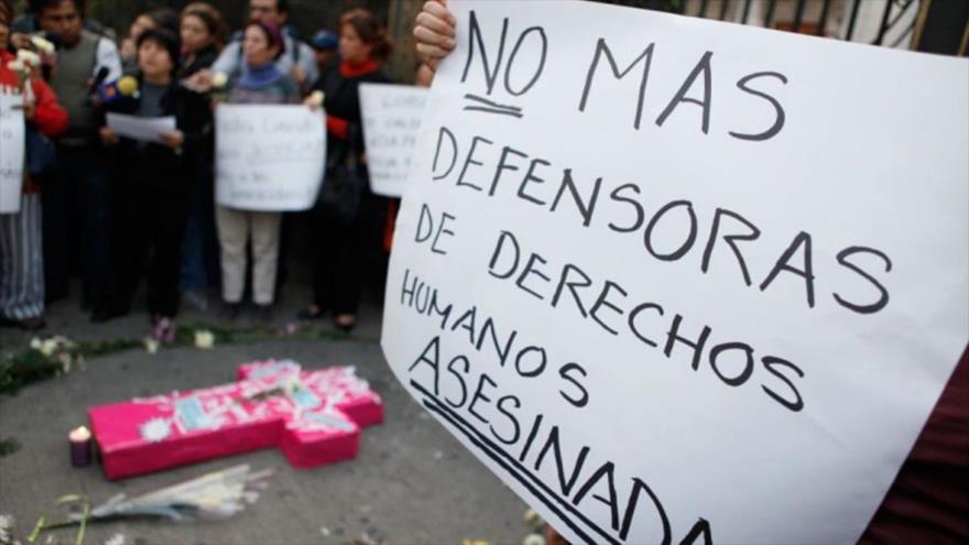 Un manifestante sostiene una pancarta a favor de los defensores de DD.HH. asesinados en Colombia. 