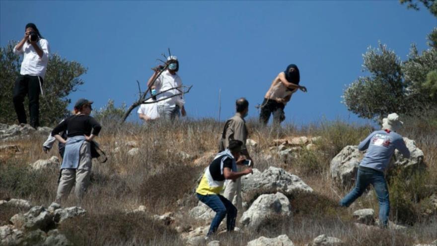 Colonos israelíes enmascarados atacan a palestinos en la Cisjordania ocupada, 7 de octubre de 2020. (Foto: AFP)