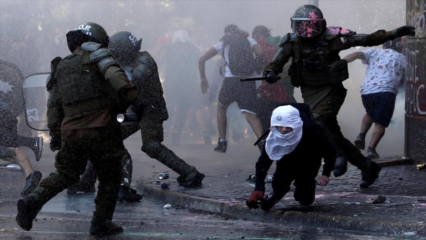 Carabineros reprimen a un manifestante durante el estallido social en Chile.