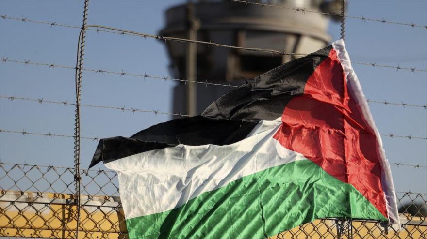 Una bandera palestina en la valla de la prisión israelí de Ofer cerca de Ramalá en la Cisjordania ocupada, 12 de julio de 2021. (Foto: AFP) 