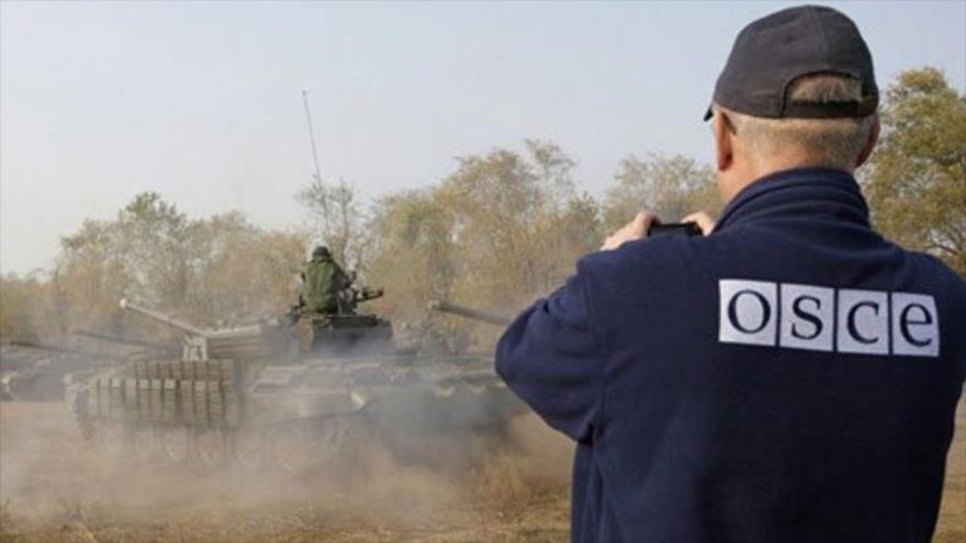 Un observador de la Organización para la Seguridad y la Cooperación en Europa (OSCE) está sacando foto a un tanque. 