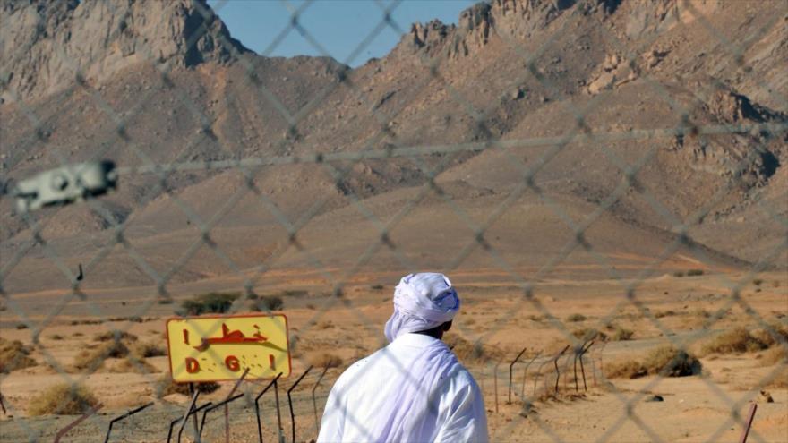 Un hombre pasa junto a una valla en la entrada de un antiguo sitio francés de prueba de bombas nucleares en Argelia, 25 de febrero de 2010. (Foto: AFP)
