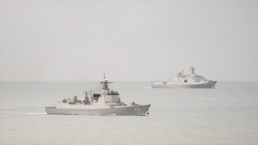 Un destructor de misiles guiados de la Marina china (izq.) y un buque de transporte anfibio entran en el mar de Coral, 18 de febrero de 2022. (Foto: AFP)