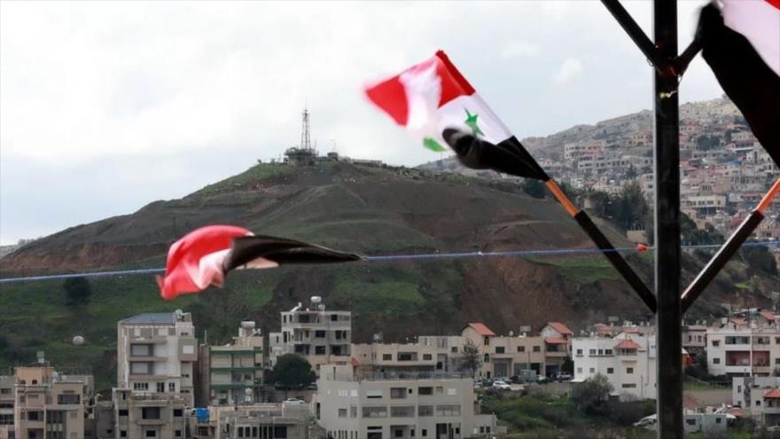 Las banderas nacionales sirias ondean en la ciudad siria de Ain al-Tineh, cerca de los altos del Golán ocupados por Israel.