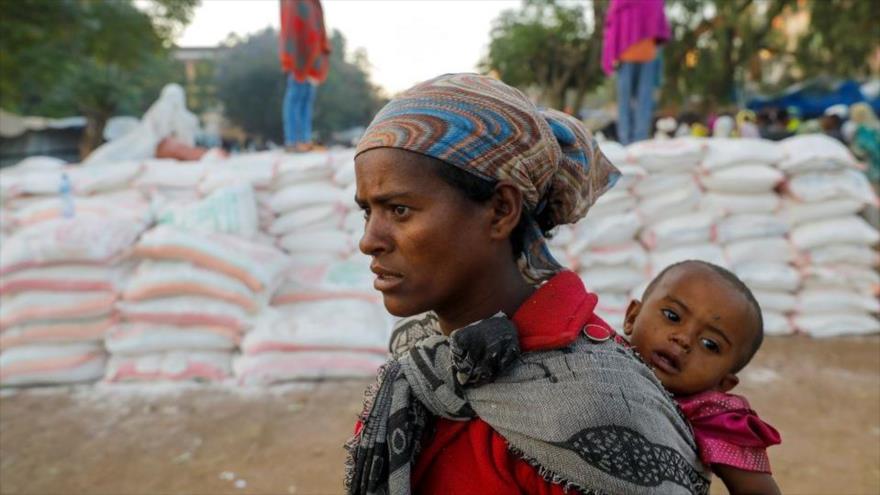 Una mujer africana lleva a su bebé mientras hace cola para recibir alimentos en una escuela en Etiopía, 15 de marzo de 2021. (Foto: Reuters)