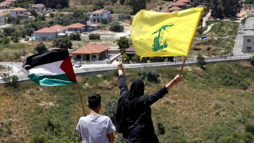 Libaneses ondean banderas de Palestina y de Hezbolá en la frontera con la Palestina ocupada en la aldea de Kfar Kila, 15 de mayo de 2021. (Foto: AP)