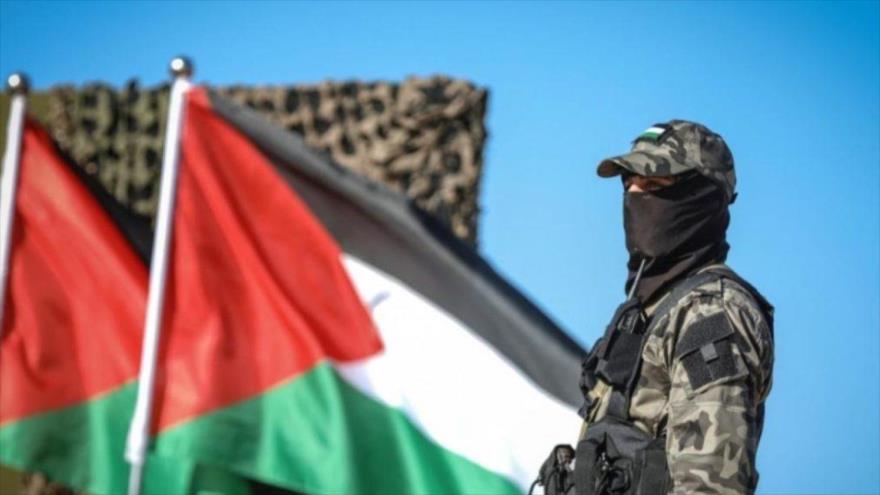 Un combatiente junto a las banderas nacionales de Palestina.