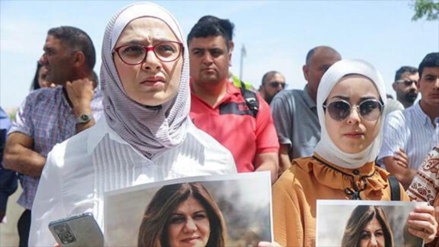 Mujeres sostienen imágenes de la reportera de Al Jazeera Shireen Abu Akleh, asesinada durante una redada israelí en Cisjordania el 11 de mayo de 2022.