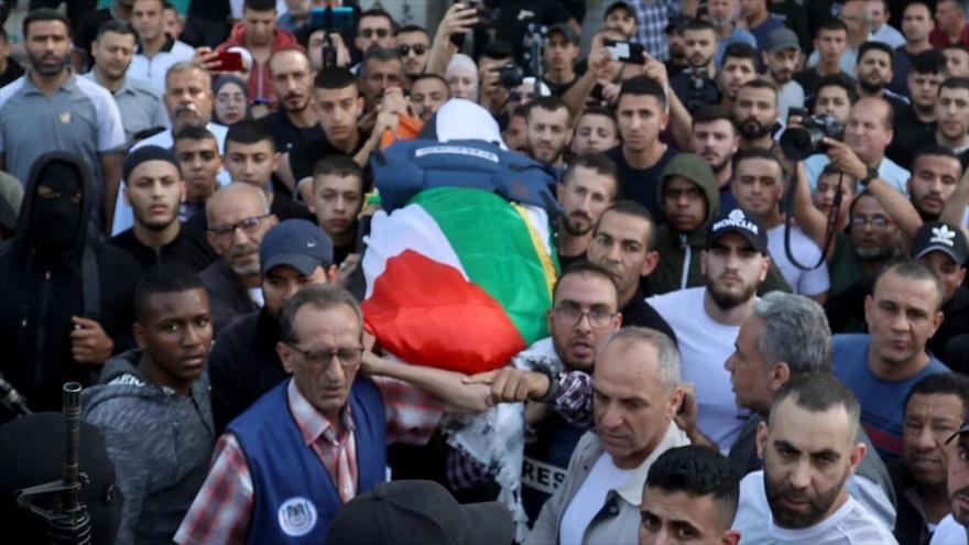 Dolientes palestinos llevan el cuerpo de Abu Akleh, periodista asesinada por las tropas israelíes en Cisjordania, 12 de mayo de 2022. (Foto: AFP)