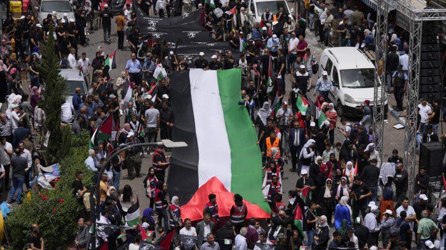 Palestinos llevan bandera nacional durante una manifestación en el Día de la Nakba, Ramalá, Palestina, 15 de mayo de 2022. (Foto: AP)