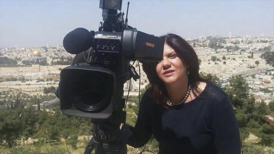 La periodista palestina Shireen Abu Akleh se ve junto a una cámara con vista de la Ciudad Vieja de Al-Quds (Jerusalén) de fondo.