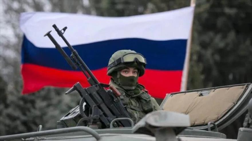 Una bandera de Rusia se ve detrás de un soldado del Ejército ruso.