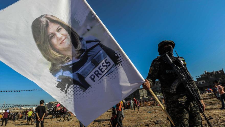 Combatiente palestino sostiene una pancarta con imagen de la periodista Shireen Abu Akleh, asesinado a tiros, Gaza, 18 de mayo de 2022. (Foto: AFP)