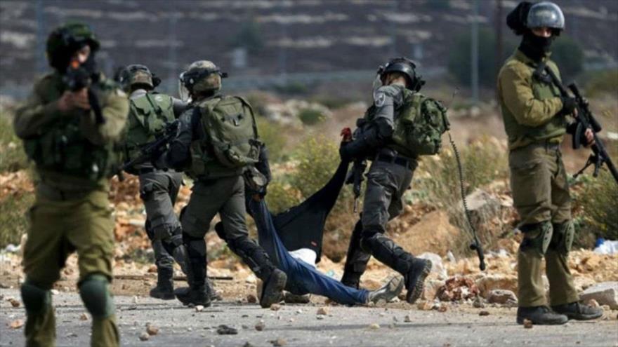 Militares israelíes detienen a un joven palestino durante una protesta en la Cisjordania ocupada.