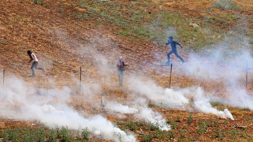 Manifestantes palestinos se alejan de los gases lacrimógenos disparados por fuerzas israelíes en la aldea de Qaryut, al sur de Nablus, Cisjordania, 24 de junio de 2022. (Foto: AFP)