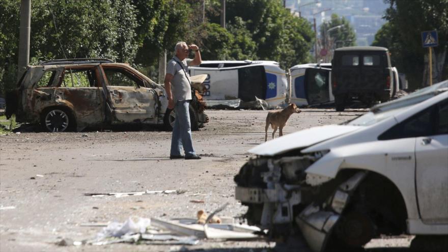 Un hombre se para junto a una barricada hecha con autos de policía destruidos en Lysychansk, 21 de junio de 2022.