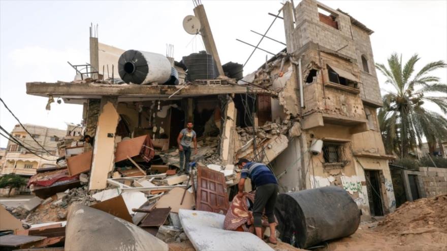 Los palestinos rescatan sus pertenencias de los escombros de su casa, destruida por los ataques aéreos israelíes en la ciudad de Gaza, agosto de 2022. (Foto: AFP)