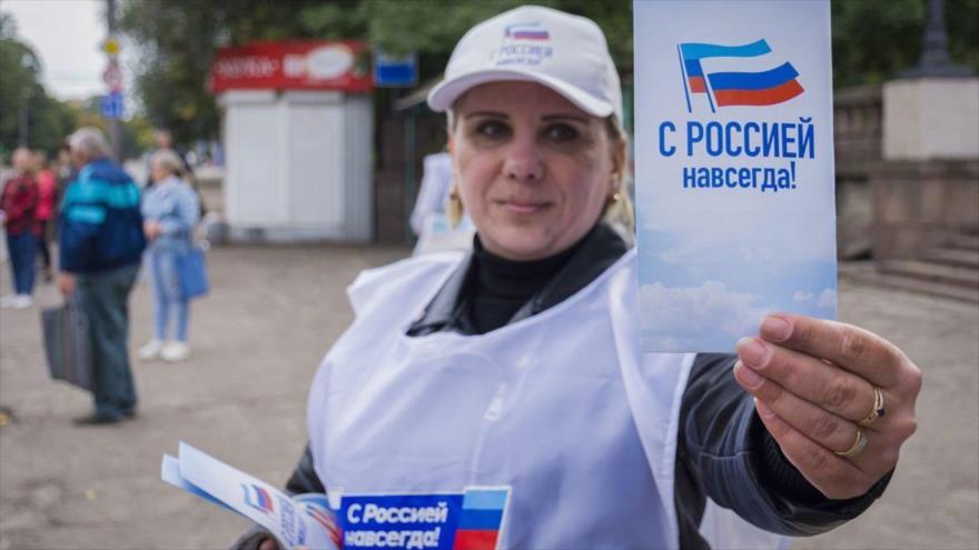 Una voluntaria reparte panfletos con el mensaje Siempre con Rusia durante la campaña para el referéndum para unirse a la Federación Rusa, en Lugansk, Ucrania. (Foto: EFE)