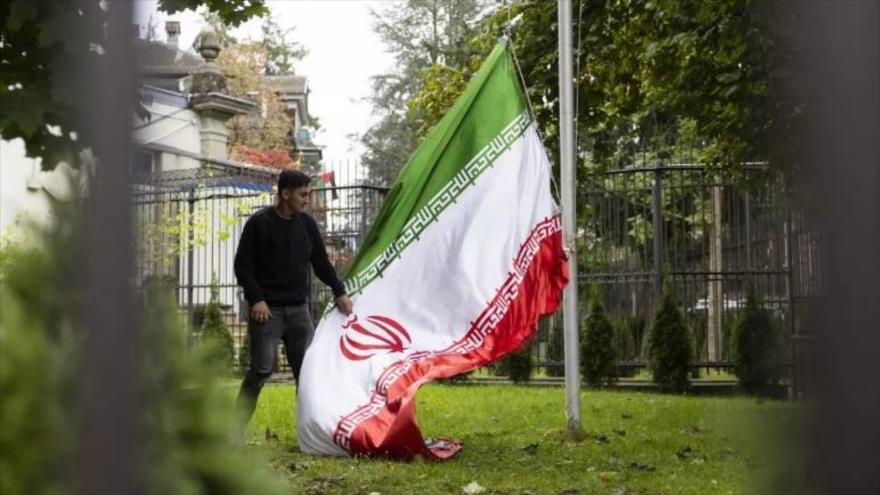 Un manifestante baja la bandera de Irán en el recinto de la embajada en Berna, Suiza, 1 de octubre de 2022. 